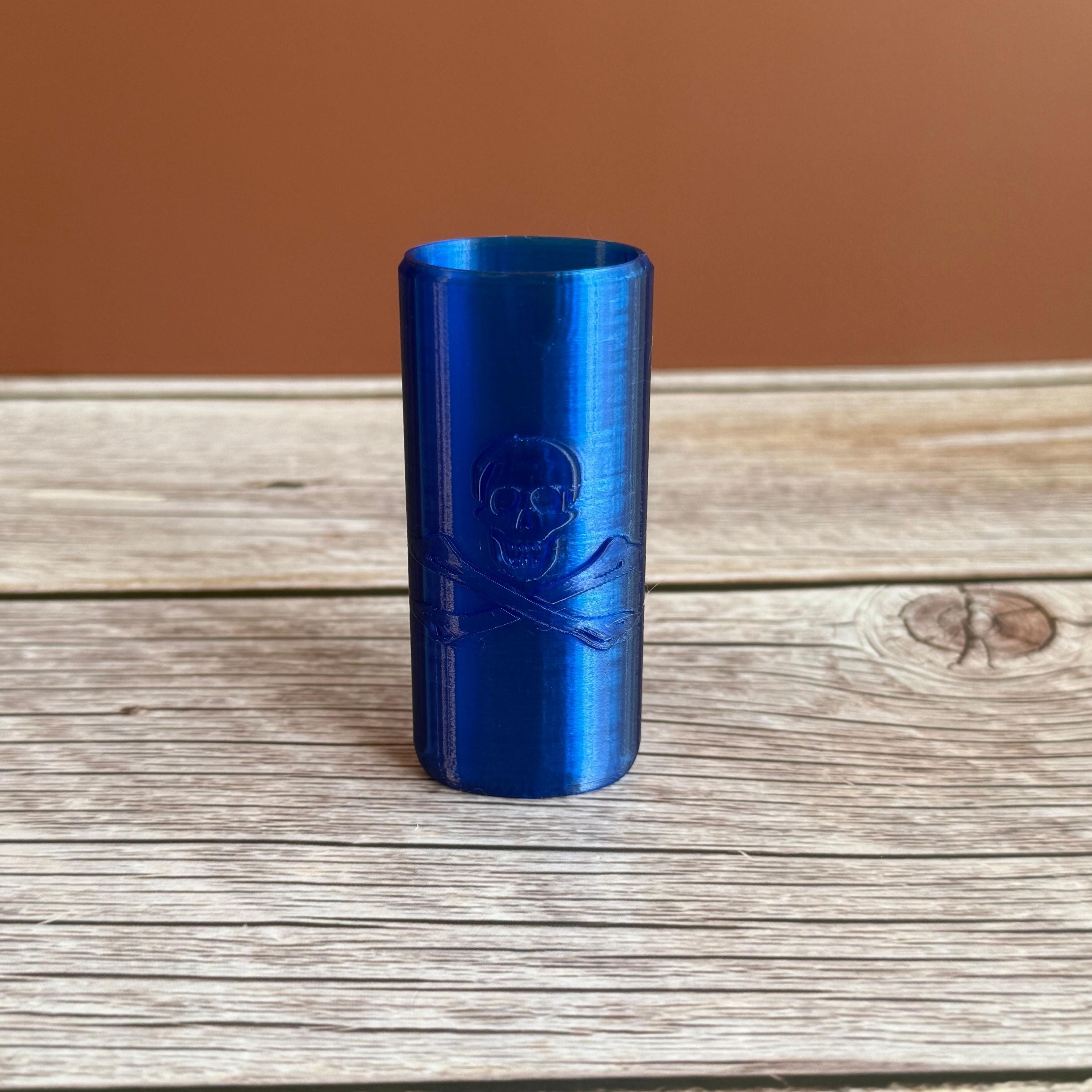 A 3D printed Bic lighter case with Skull and Crossbones design displayed in blue color on wooden surface and brown background