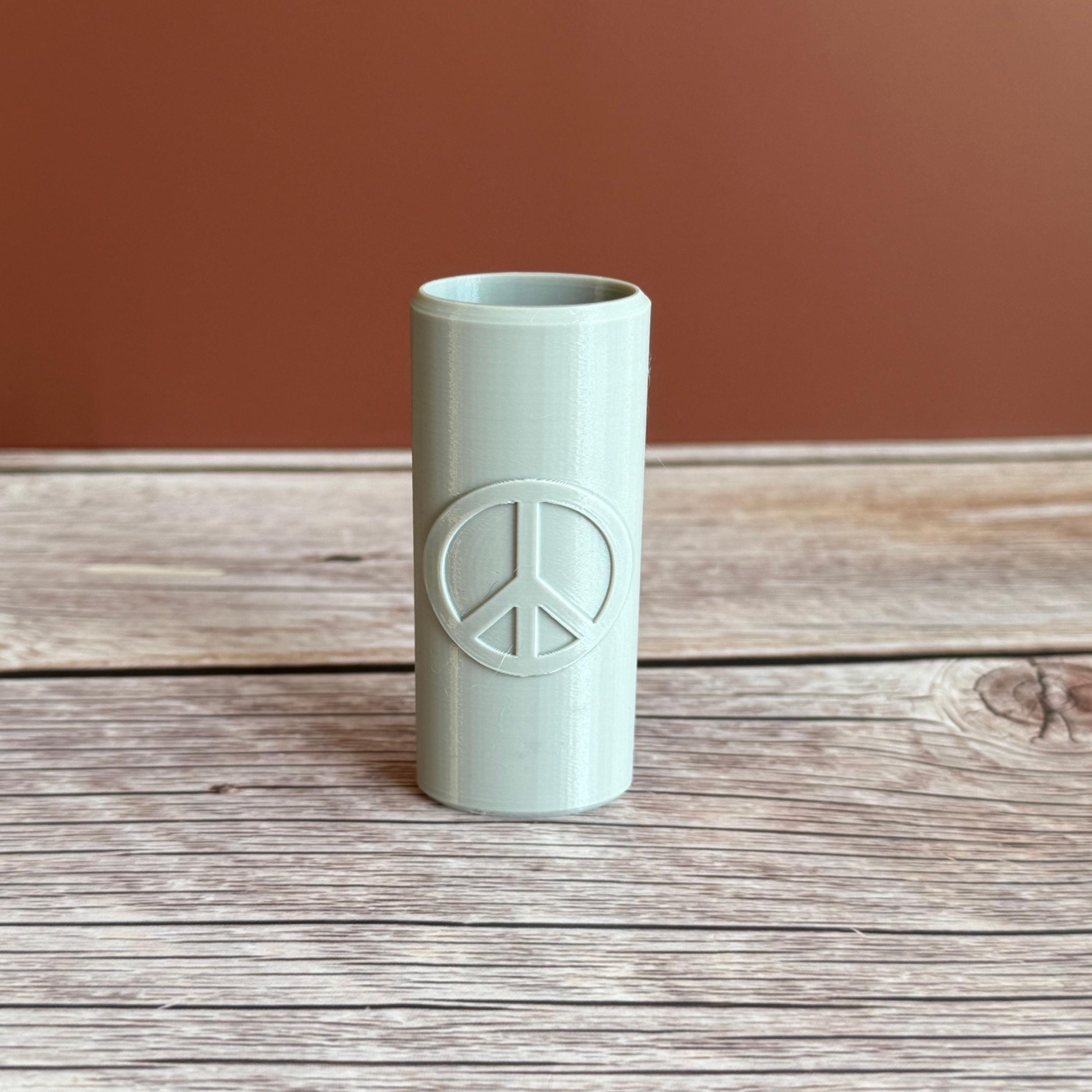 A 3D printed Bic lighter case with Peace sign design displayed in gray color on wooden surface and brown background