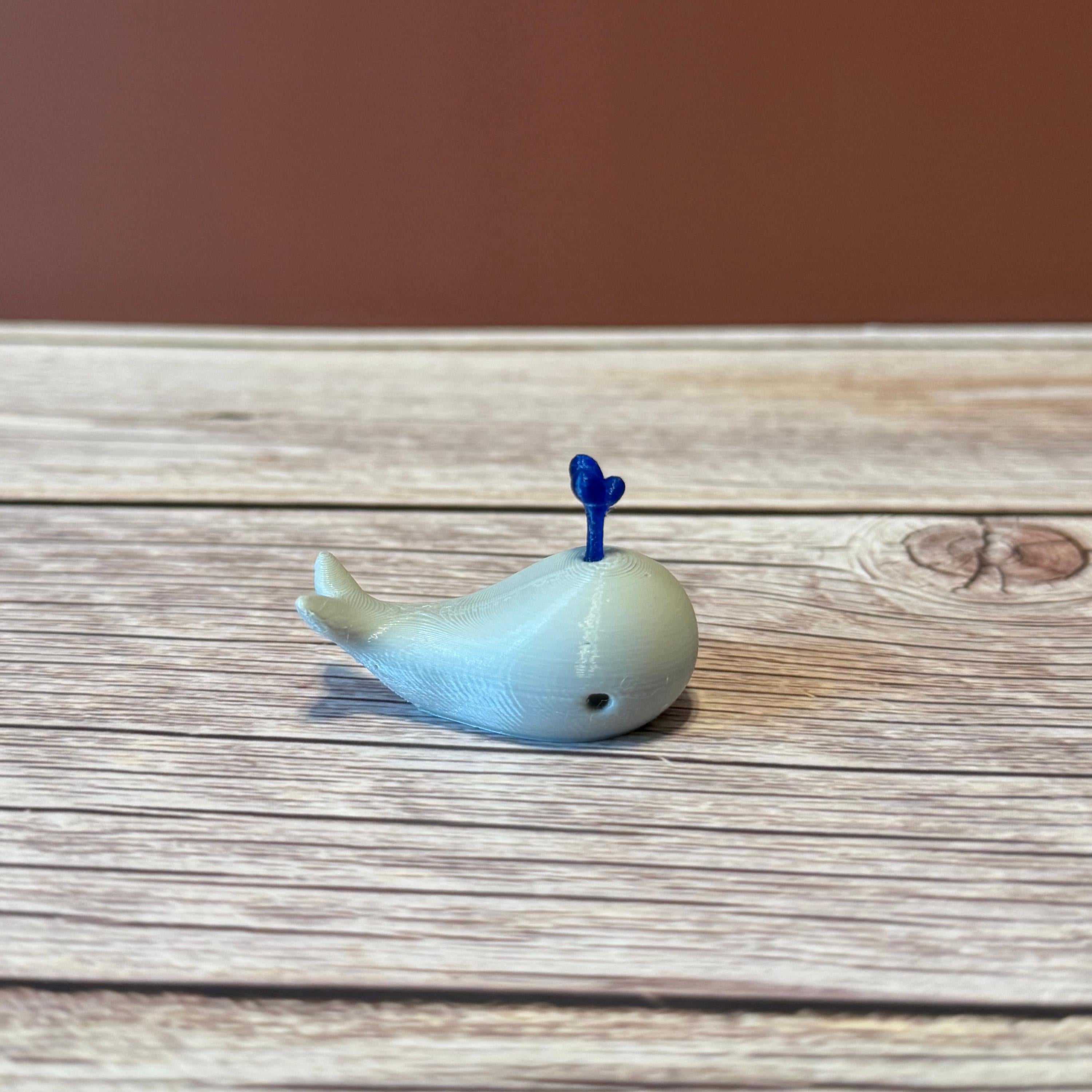 A 3D printed white whale chopstick rest with a space for holding chopsticks, placed on a wooden surface.