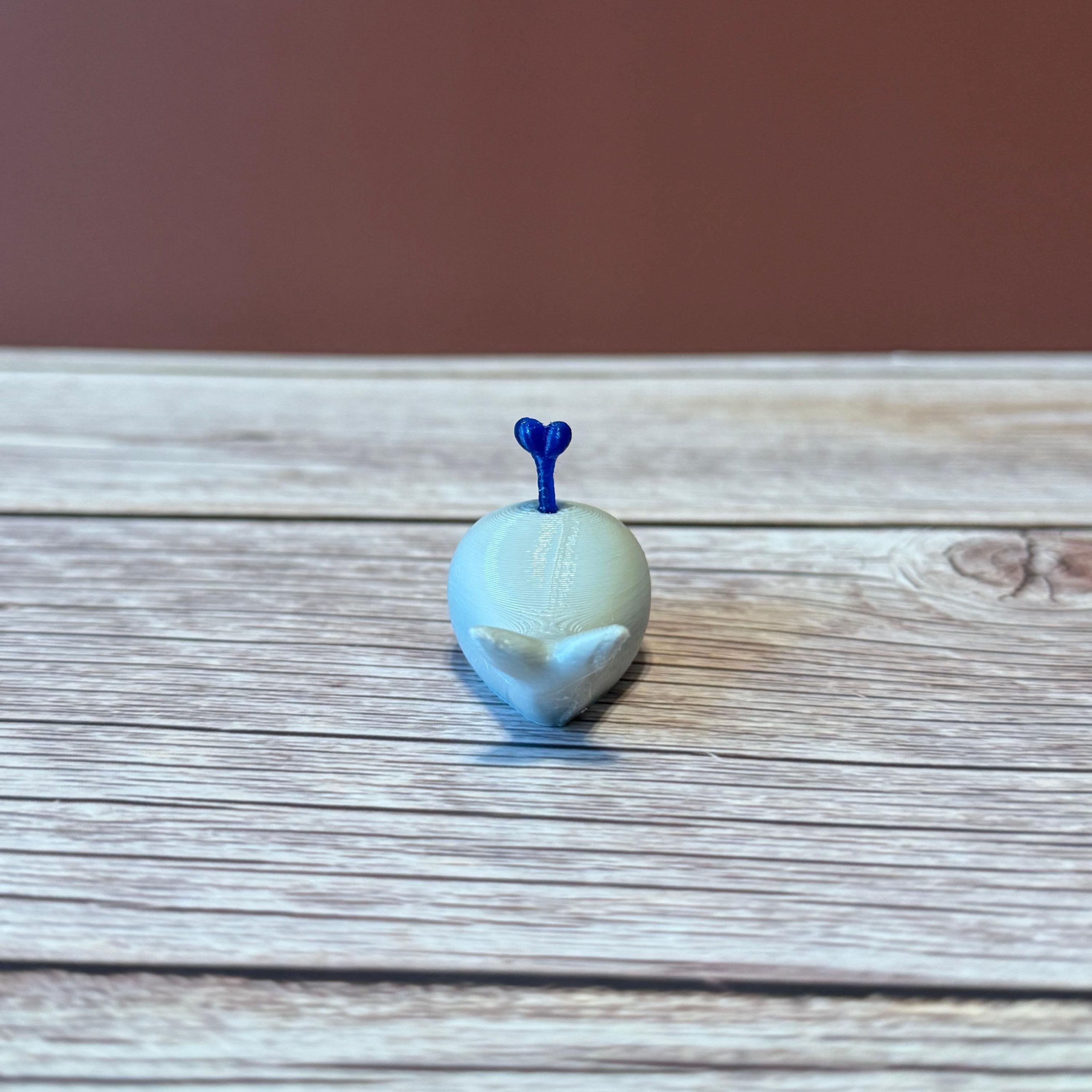 A 3D printed white whale chopstick rest with a space for holding chopsticks, placed on a wooden surface.