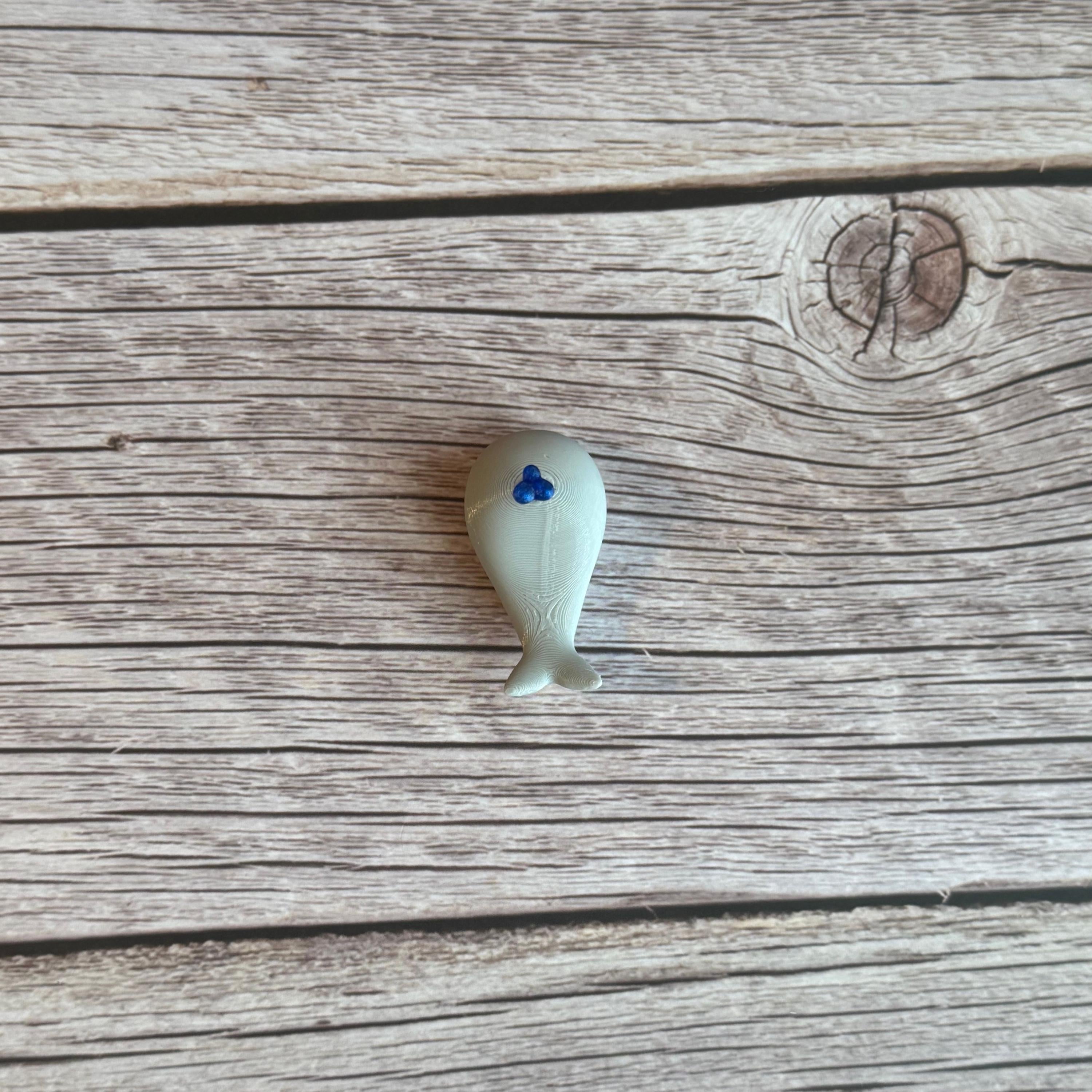 A 3D printed white whale chopstick rest with a space for holding chopsticks, placed on a wooden surface.